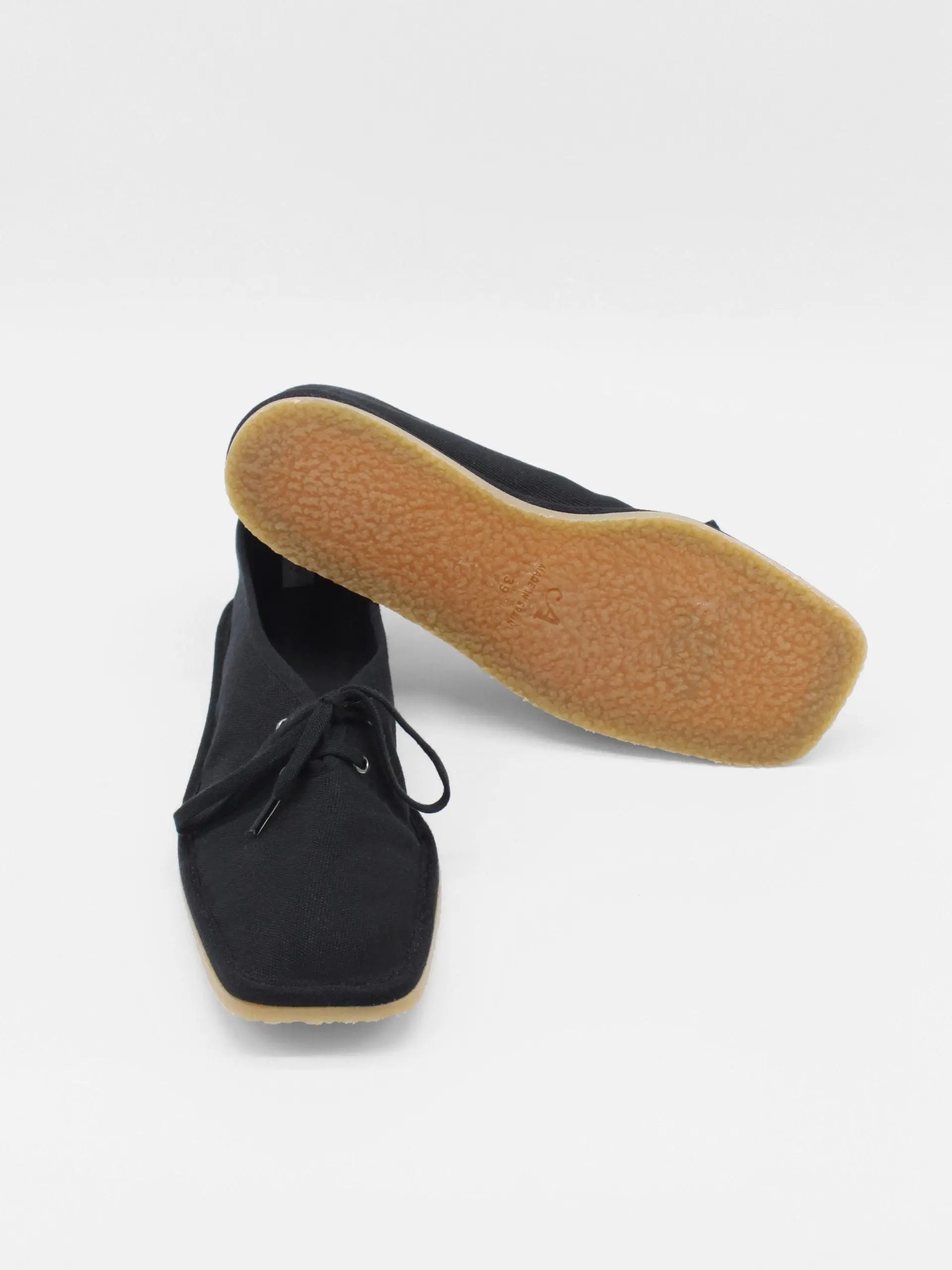 A pair of Lona Black shoes by About Arianne with a minimalist, square-toe design, positioned side by side on a white background. The shoes have black laces and appear to be made of a fabric material, reflecting the chic style found in Barcelona's finest stores.