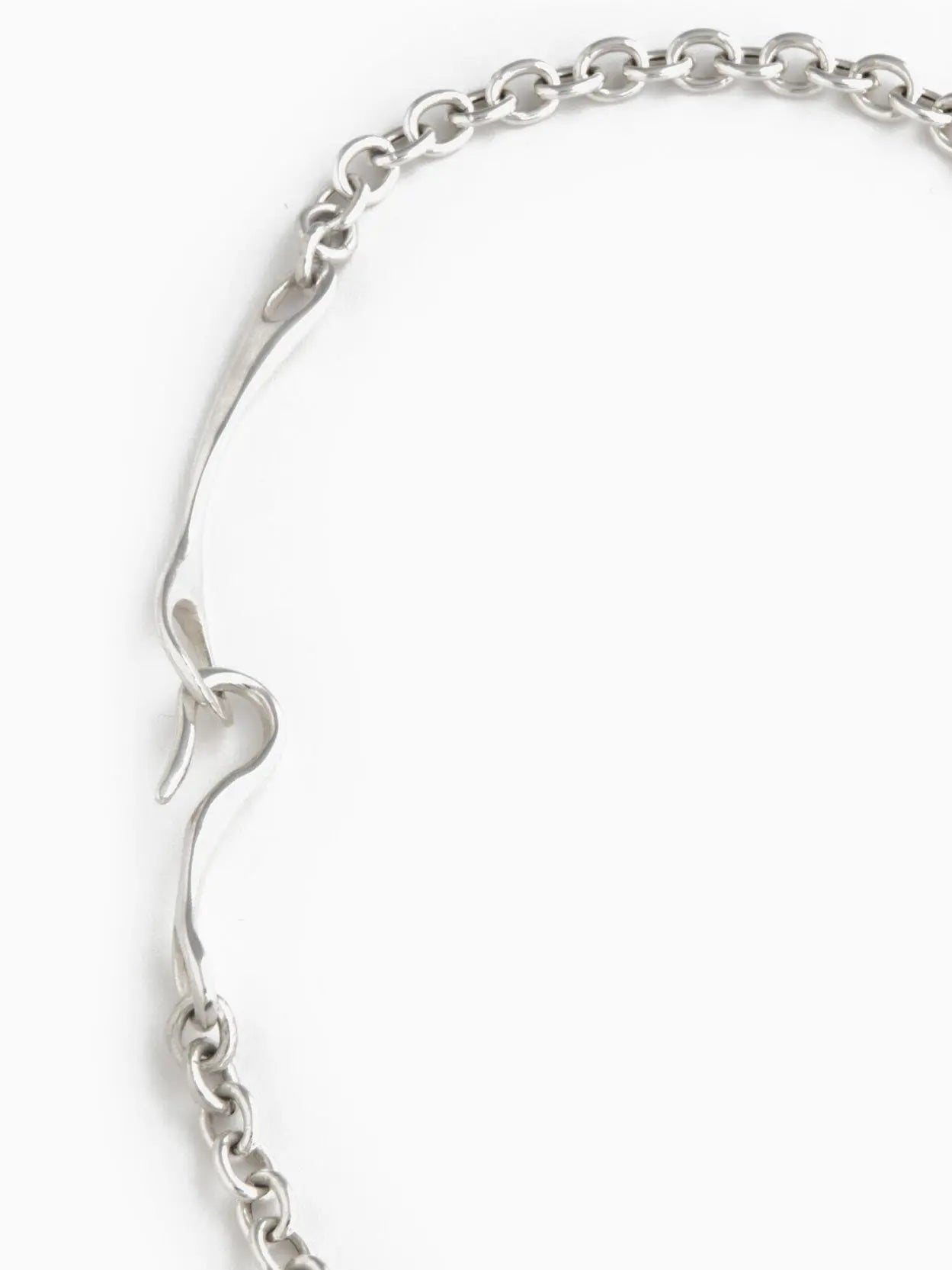A Maia Necklace from Nathalie Schreckenberg, featuring a linked chain design with a small heart-shaped clasp, laid out in an oval shape on a white background.