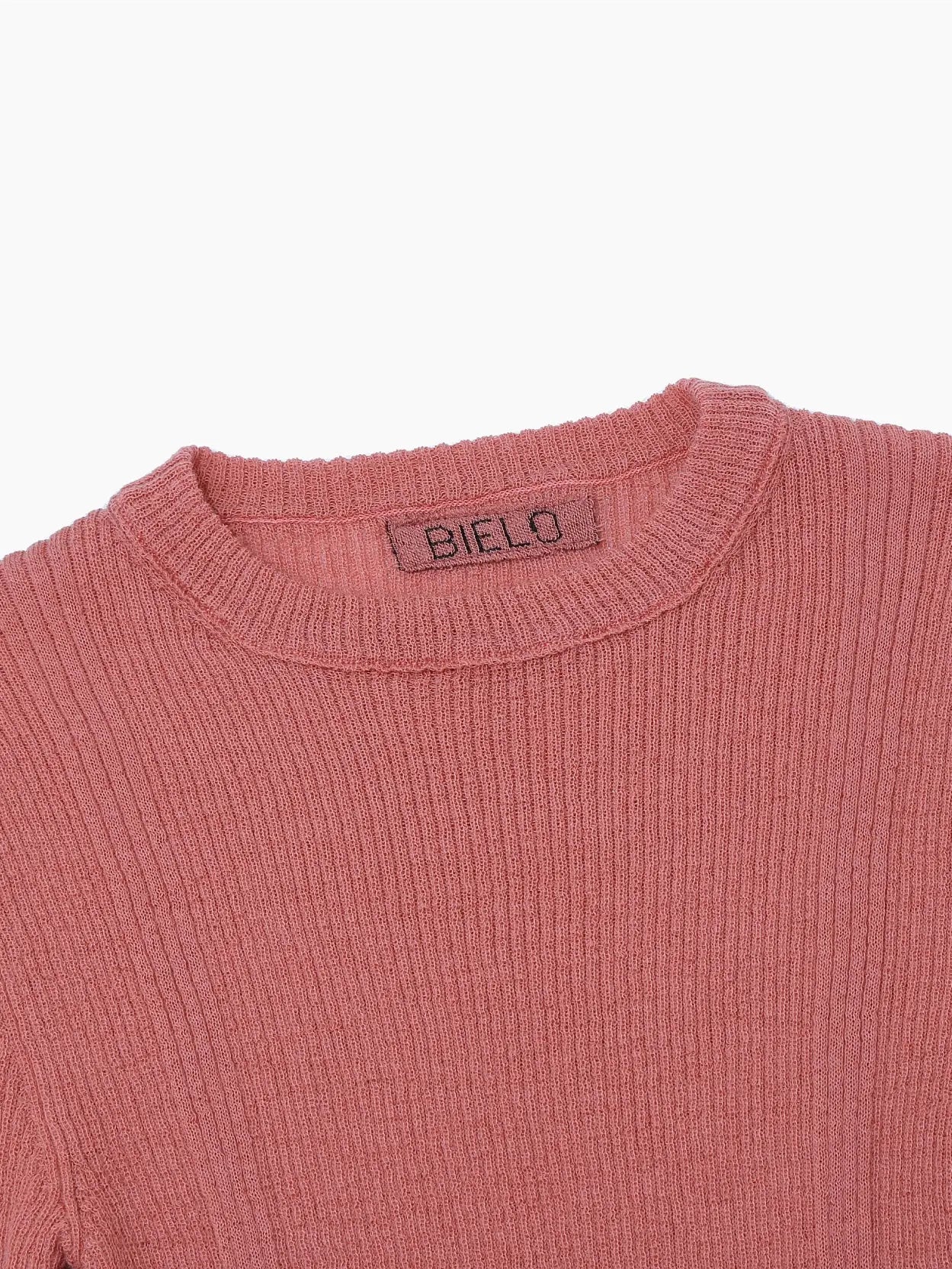 A ribbed, long-sleeve sweater in a dusty rose color is displayed against a white background. The fitted style features vertical ribbing patterns for texture and a round neckline. A small fabric tag is visible on the inside back of the neckline, available exclusively at Bassalstore in Barcelona. Product: Masla Long Sleeve Coral by Bielo.