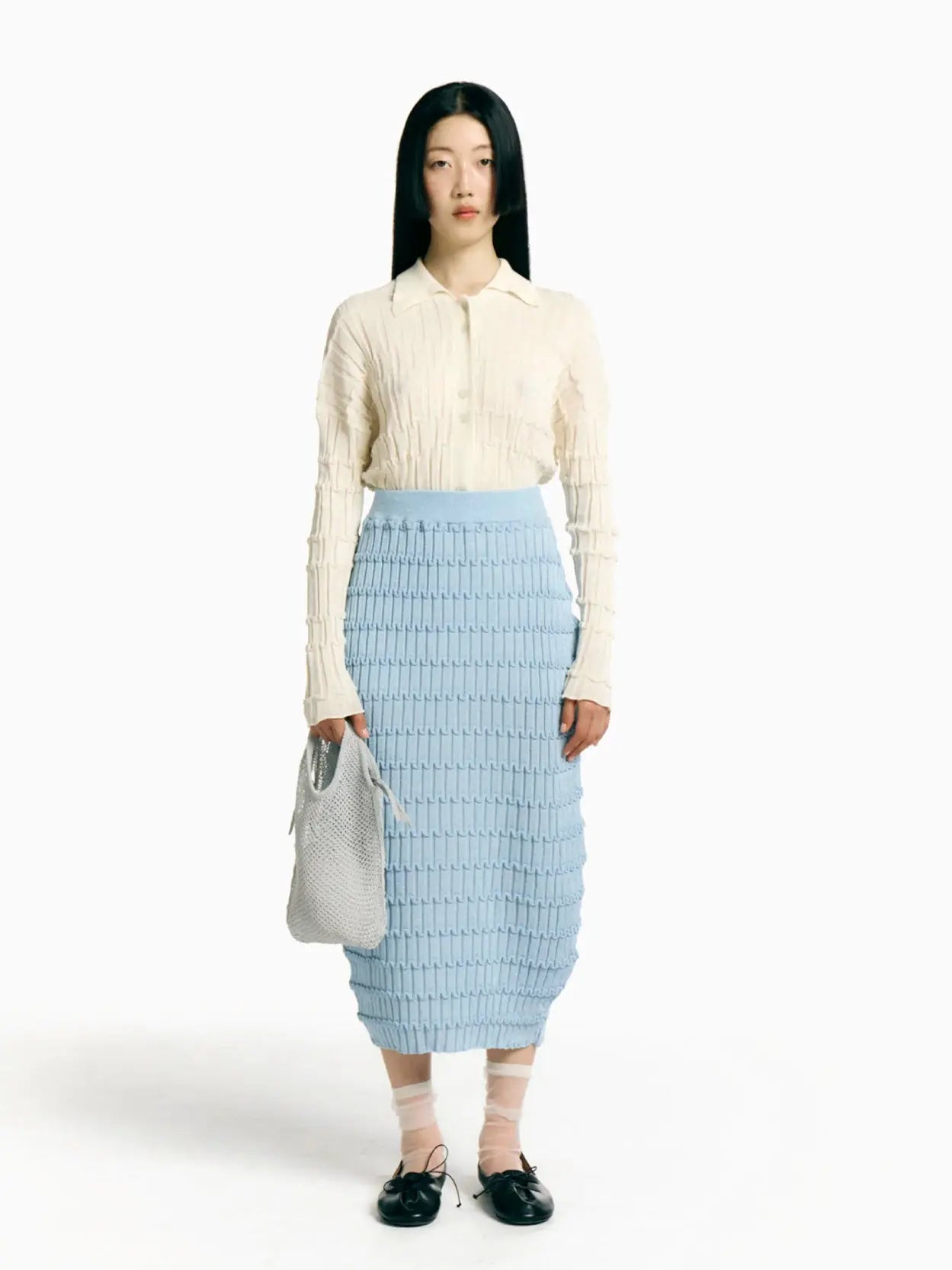 A Rus Mizuki Skirt Light Blue, knitted with a ribbed, wavy texture pattern from Bassalstore. The form-fitting skirt features an elastic waistband for a snug fit and boasts a knee-length design, displayed beautifully on a plain white background. Perfect for your next visit to Barcelona!