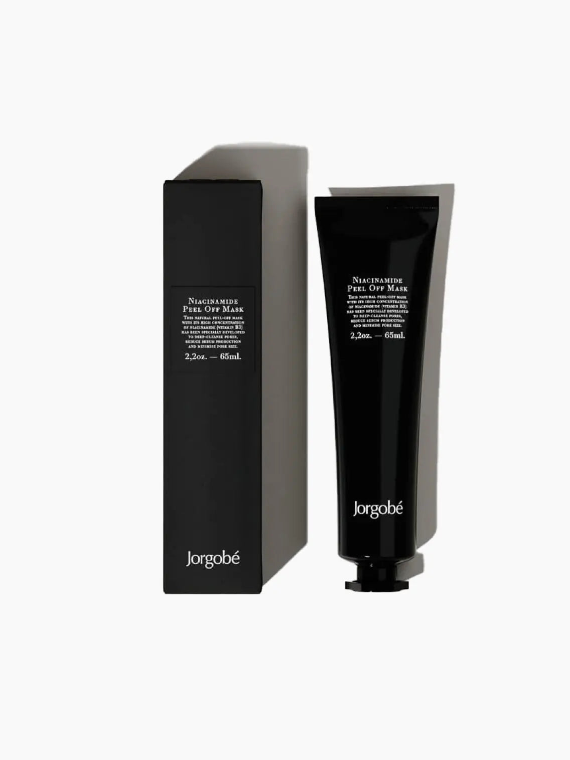 A sleek, black tube of Jorgobé Niacinamide Peel Off Mask 65ml stands next to its matching black box. Both the tube and the box are labeled with white text detailing the product's name and specifications: 2.20 oz (65 ml). Now available at Bassalstore in Barcelona.