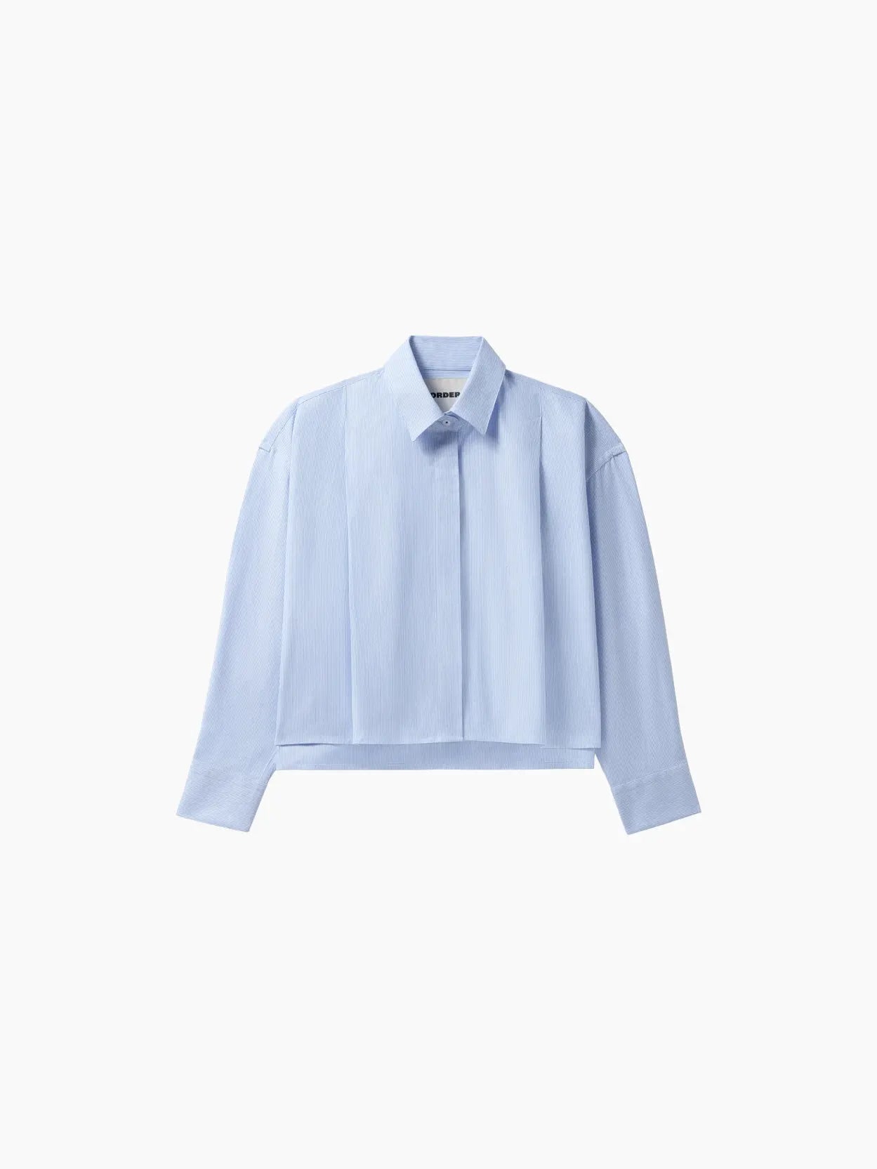 A light blue, long-sleeve collared shirt with a button-down front, seen against a white background. The Oxford Shirt by Cordera, featured in our Barcelona store, has a relaxed fit with slightly dropped shoulders and minimalist design.
