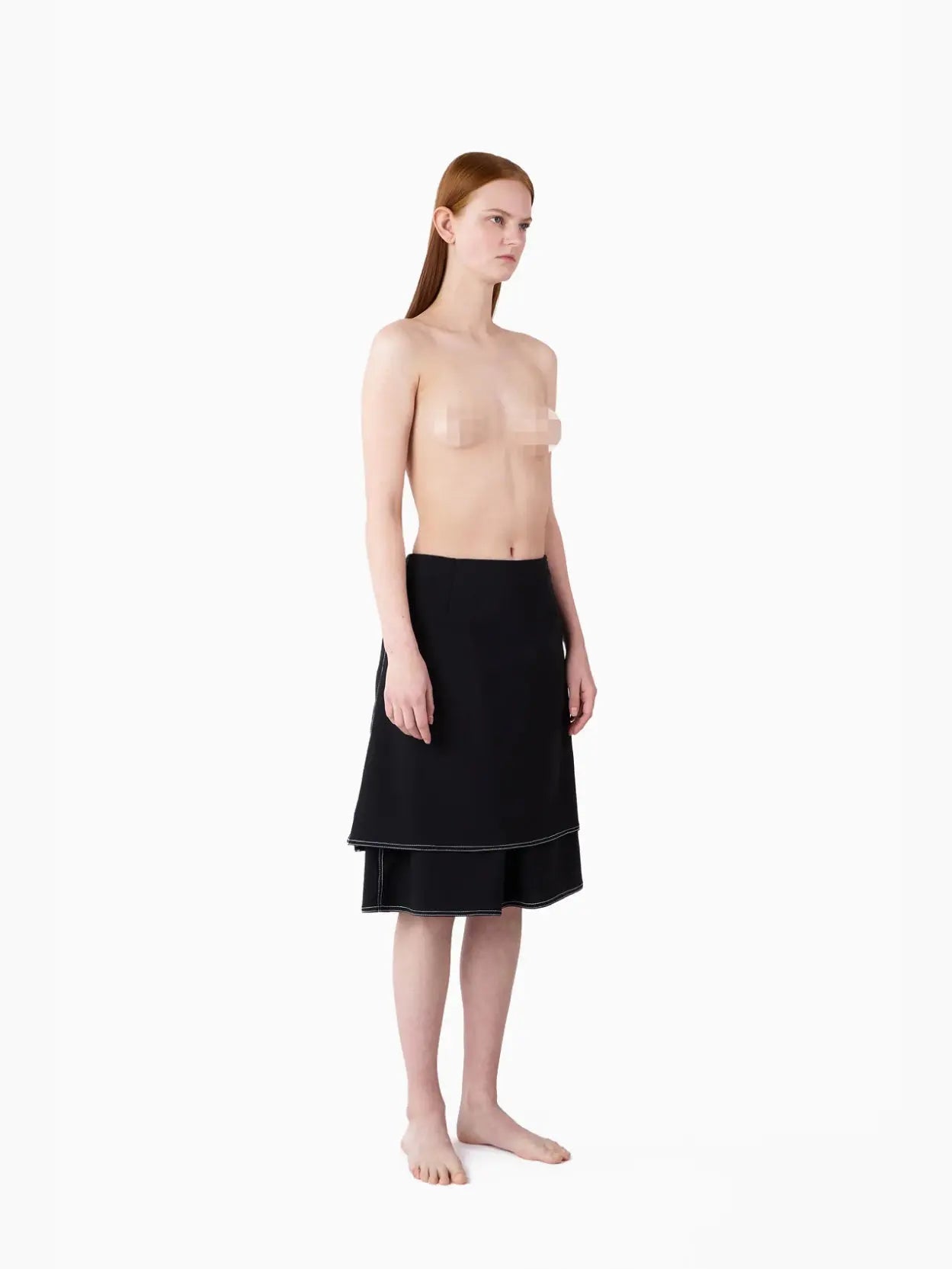 A black double-layered mini skirt with white stitching accents. The design features a layered look, with a shorter top layer and a longer underlayer, creating a stylish and modern appearance. Displayed against a white background, this chic piece is available at Bassalstore in Barcelona. The product name is Panta Skirt Black by Sunnei.