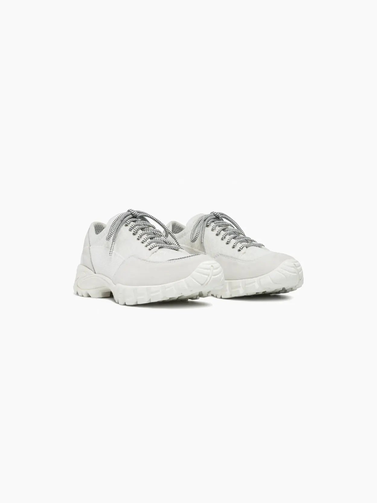 A white athletic shoe with a textured fabric upper and chunky sole, available exclusively at Bassalstore. The Possagno White Suede by Diemme features a lace-up design with grey laces and subtle decorative stitching. The sole has a rugged tread pattern for grip, echoing the dynamic energy of Barcelona's bustling streets.