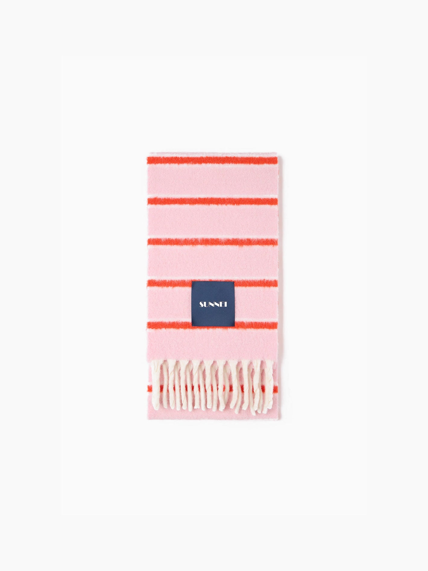 The Pink Stripes Scarf by Sunnei, made from luxurious alpaca wool, is artistically designed with pink and red stripes and accented with white fringes at the edges. Elegantly folded, it bears a dark blue label with white text. Crafted in Italy, this exquisite piece stands out beautifully against a plain white background.