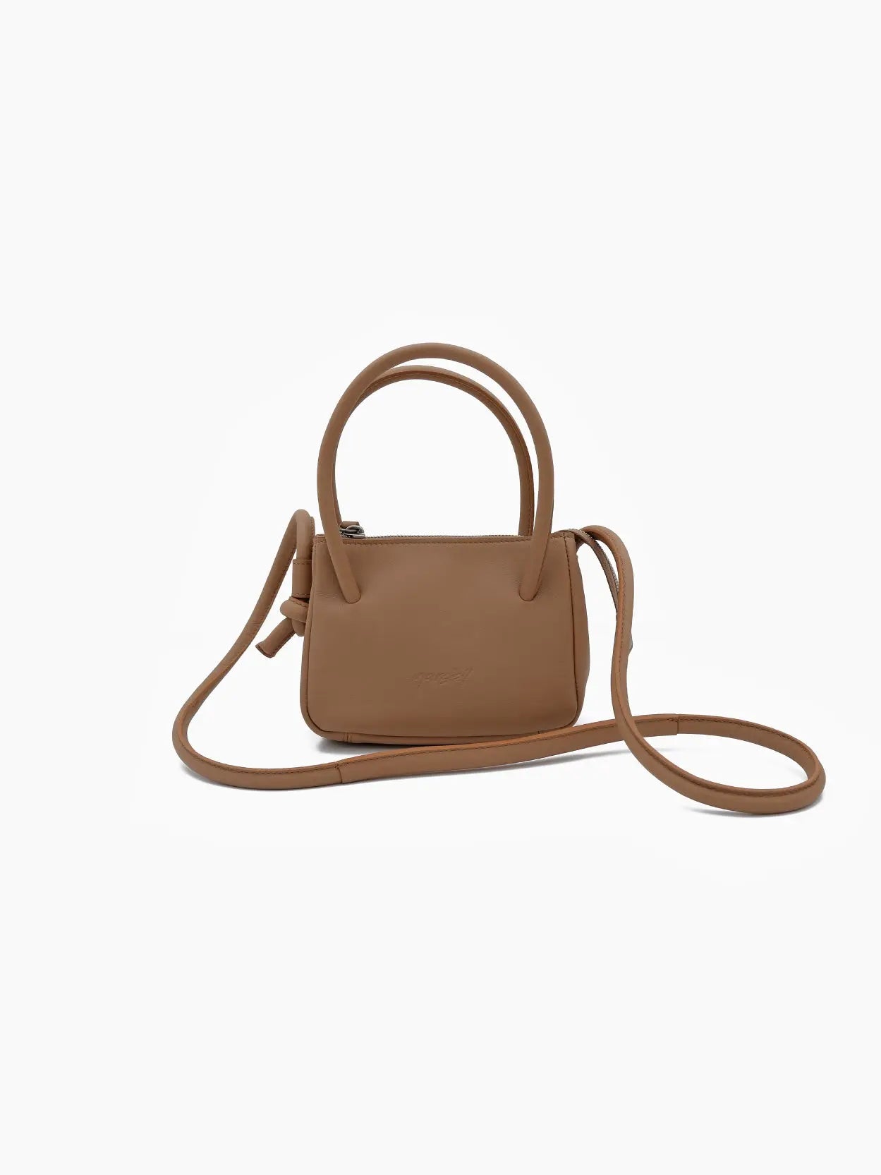 A small brown crossbody Sacco Piccolo Mini Bag Hazelnut with a minimalist design, featuring rounded handles, a long adjustable strap, and a subtle embossed logo on the front. The bag by Marsèll, available at Bassalstore Barcelona, is set against a plain white background.