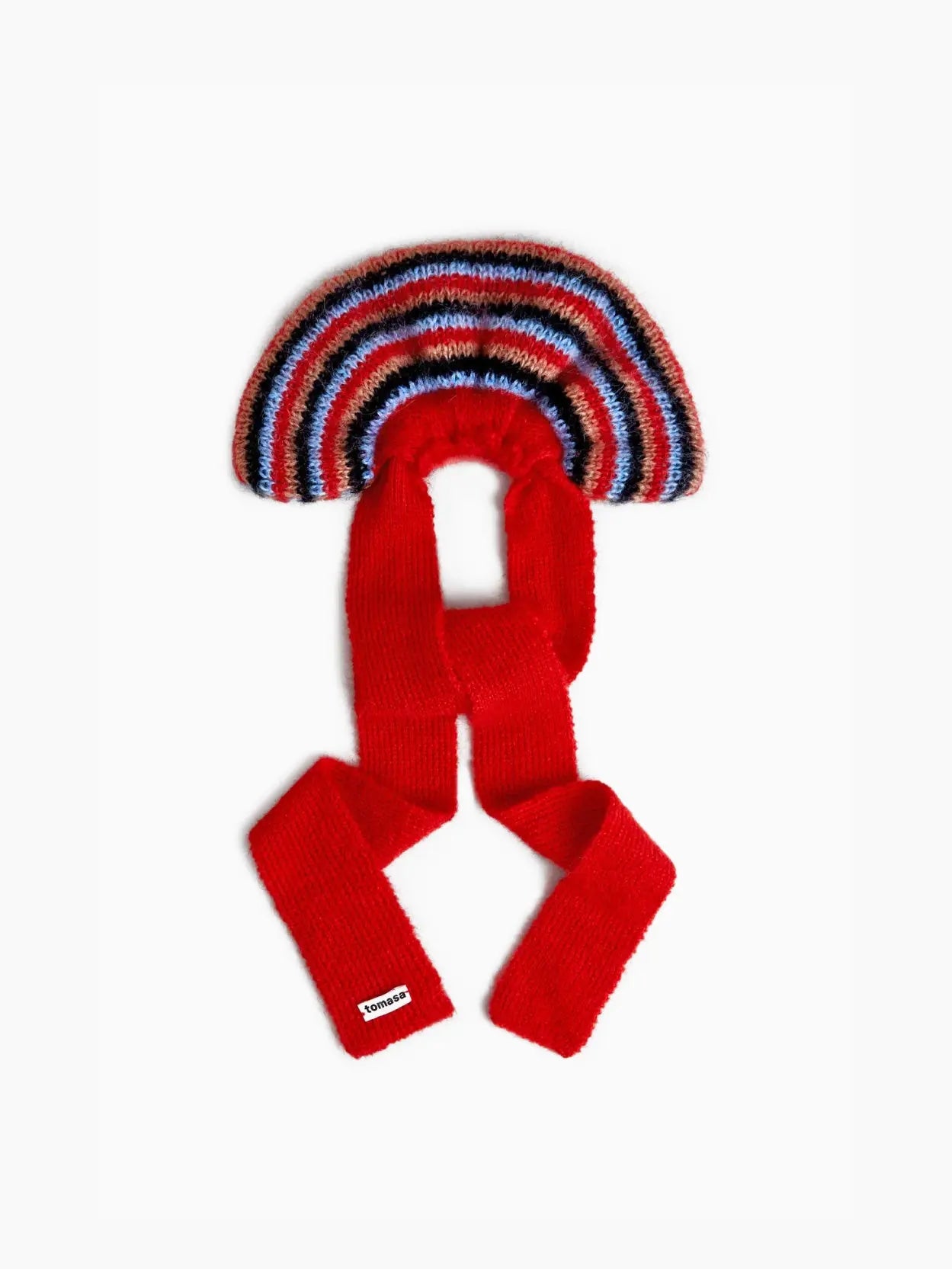 A colorful Serena Bow Scrunchie with a curved section featuring blue, white, red, and black stripes, and two long, bright red tails. A small label from Tomasa is visible on one of the red tails. The background is plain white.