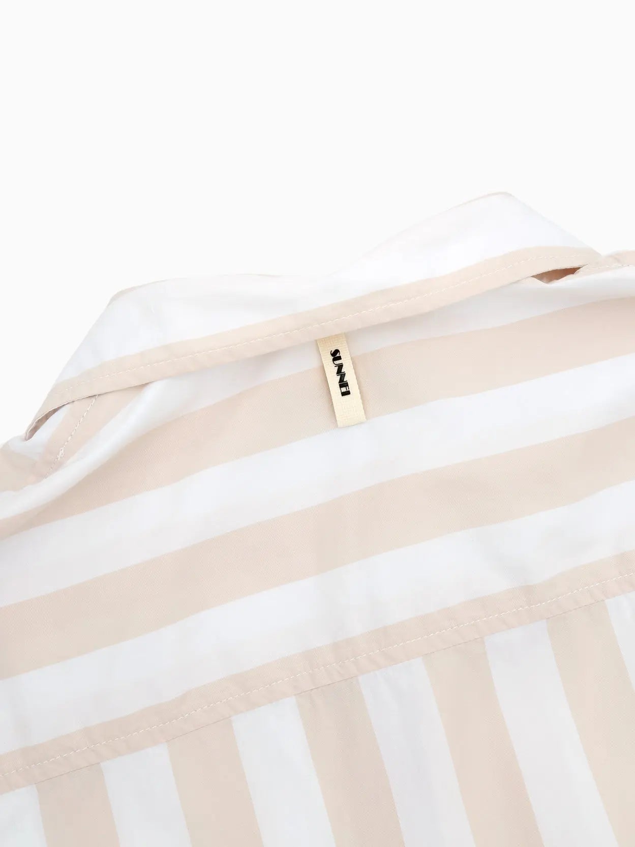 A short-sleeved, button-up shirt with vertical beige and white stripes. It features a spread collar and front buttons, creating a casual yet stylish look suitable for warm weather. Perfect for those sunny days in Barcelona, find the Short Sleeve Shirt Off White by Sunnei now at Bassalstore for your wardrobe refresh.
