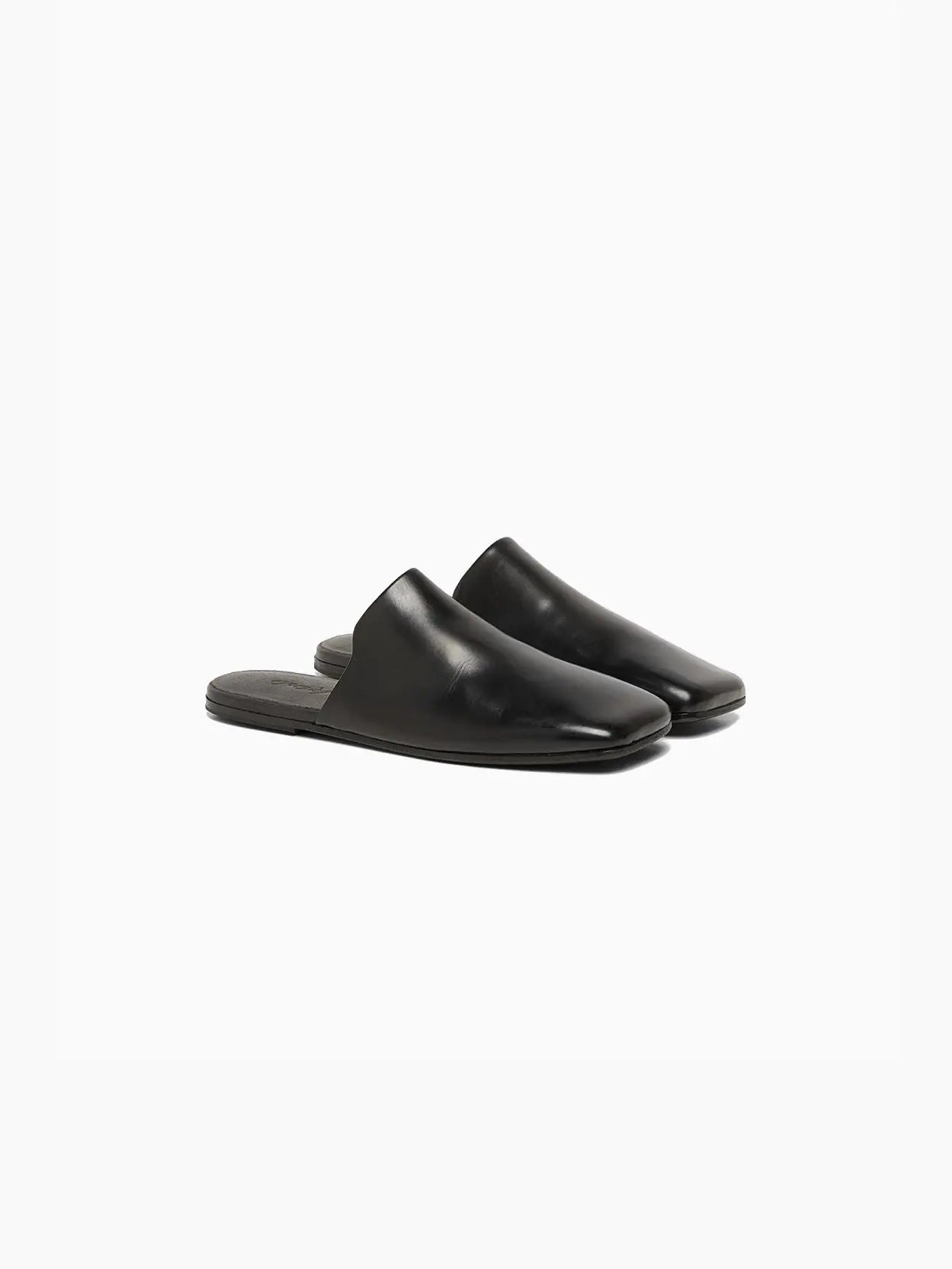 A sleek black leather mule slipper with a flat sole, open back, and round toe design on a white background. Available at Bassalstore in Barcelona, the Spatolona Mule Black by Marsèll features a smooth, polished finish and a low-profile silhouette.