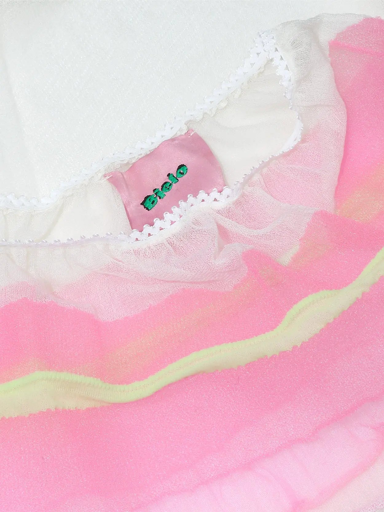 An image of the Spencer Skirt Ecru available at BassalStore, featuring a white lower section and a pink upper section. The skirt has two horizontal lime-green stripes near the top and an elastic waistband for a comfortable fit. This stylish item is brought to you by Bielo.