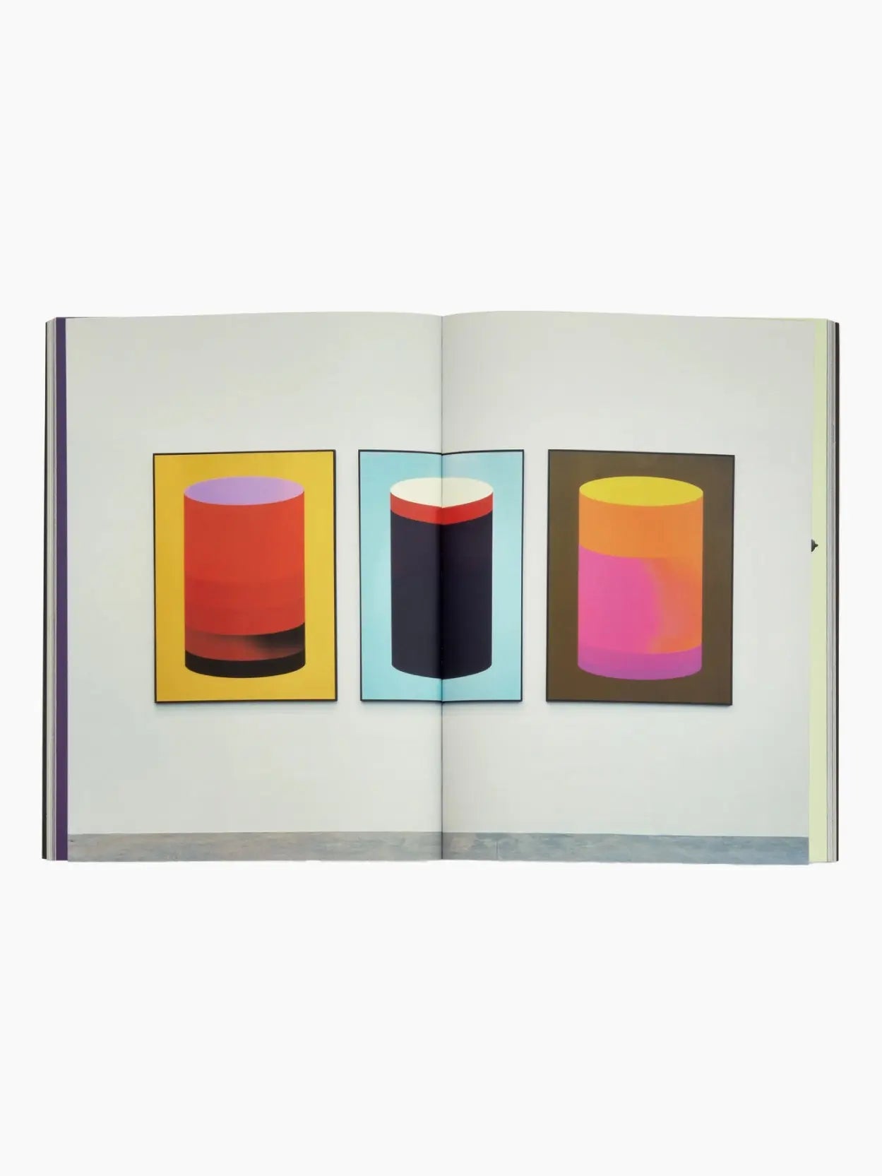 A book titled "Stefan Sagmeister: Now Is Better" by Phaidon stands upright against a white background. Its cover features artwork of a classical painting overlaid with graphic shapes: a blue cylinder, a yellow circle, and a red semicircular shape. Available at Bassalstore in Barcelona.