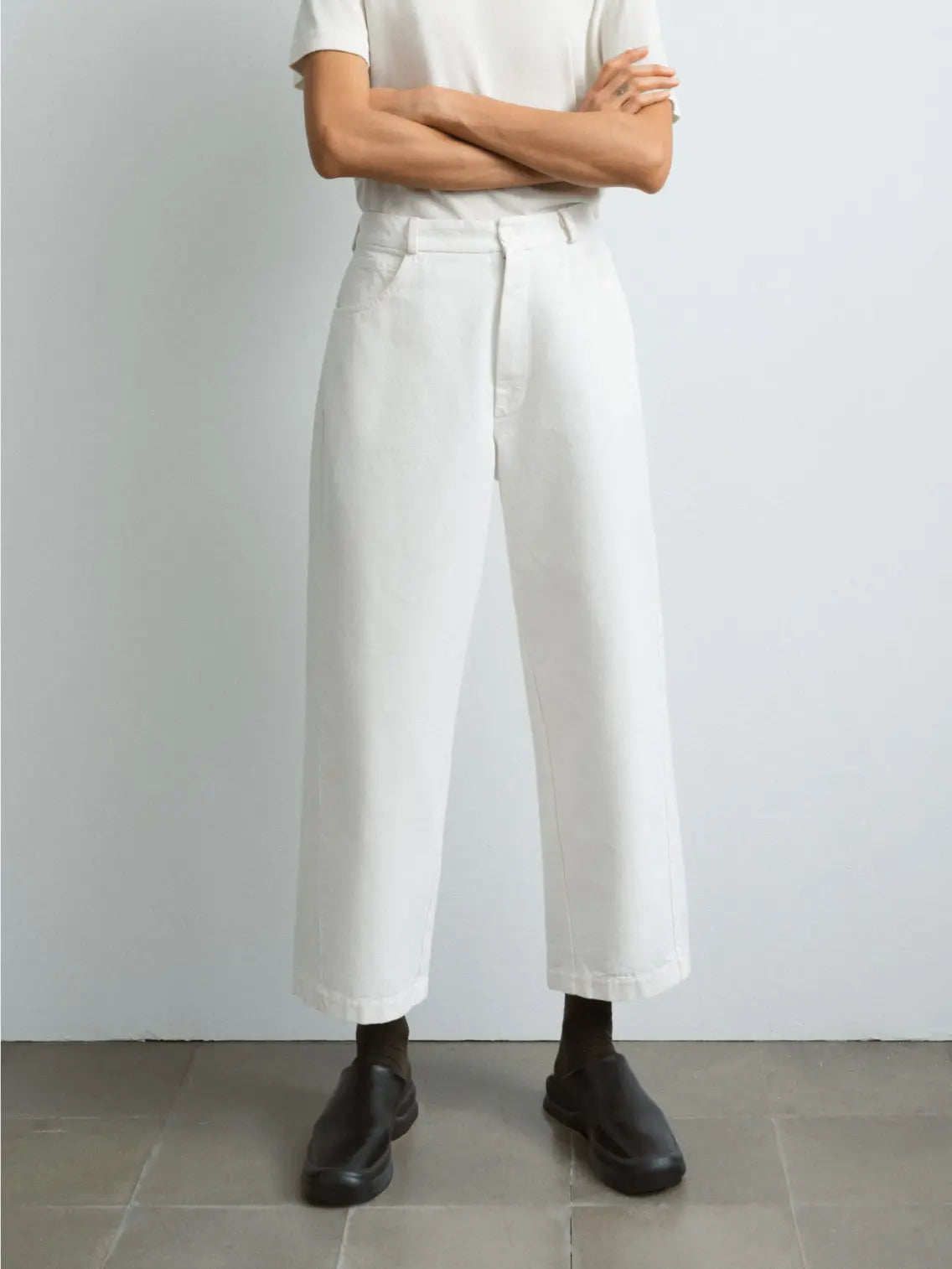 A pair of Straight Denim Pants Off-White from Cordera is displayed against a plain white background. The pants feature a button closure and belt loops at the waist, along with front pockets. The fabric appears smooth and slightly structured, embodying the chic style of Barcelona fashion.