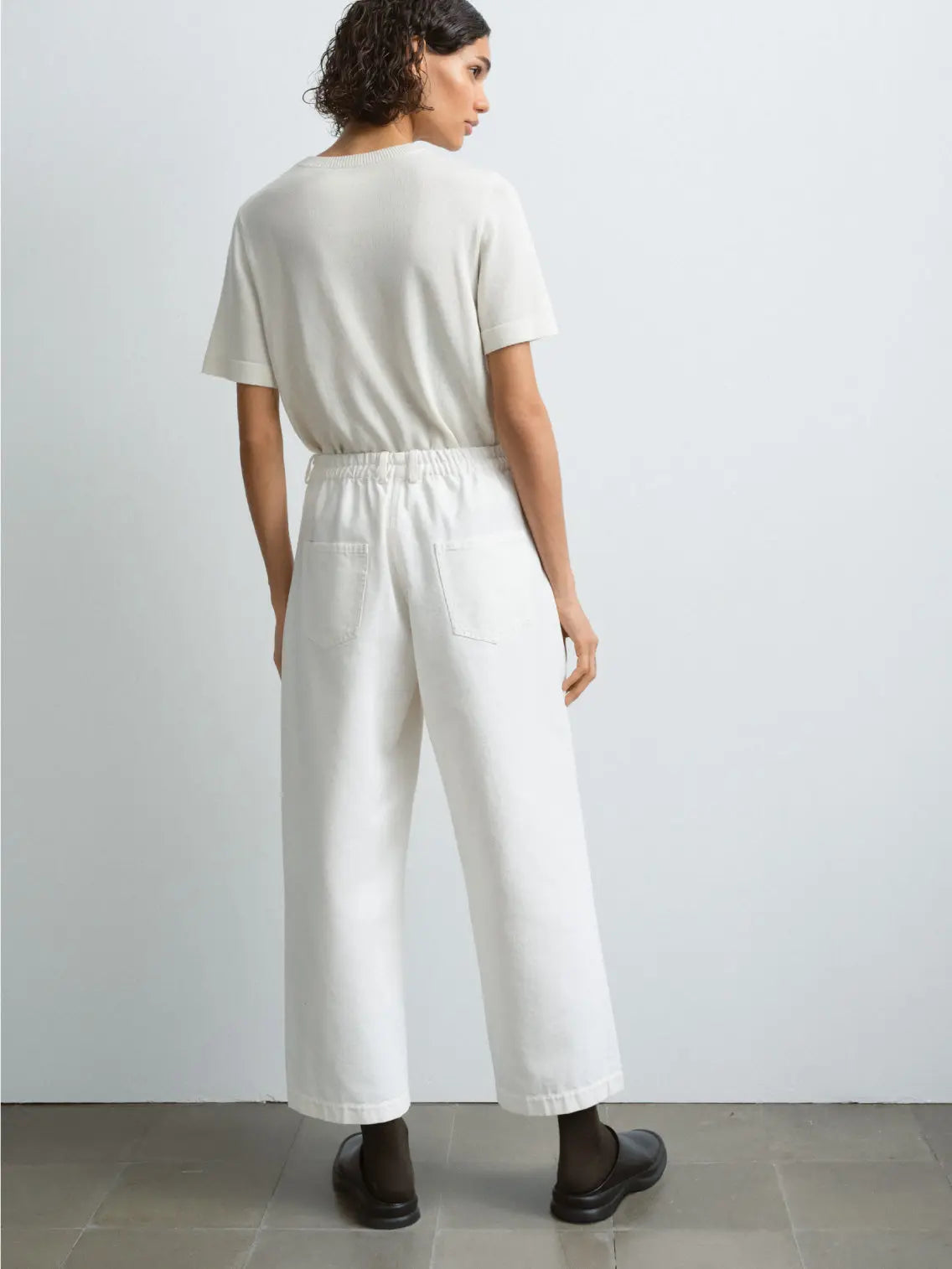 A pair of Straight Denim Pants Off-White from Cordera is displayed against a plain white background. The pants feature a button closure and belt loops at the waist, along with front pockets. The fabric appears smooth and slightly structured, embodying the chic style of Barcelona fashion.