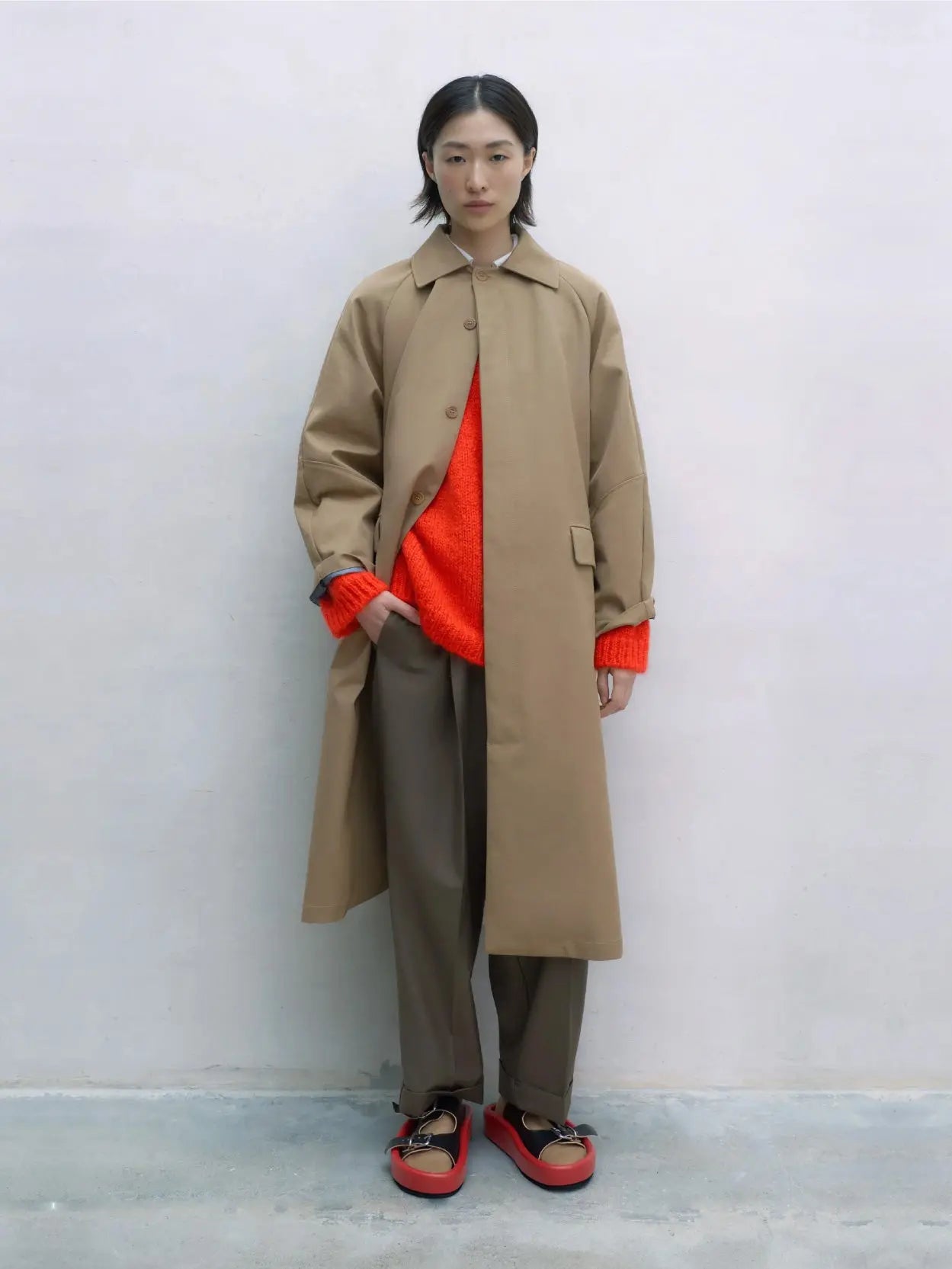 A long beige Trench Coat Camel with a collared neckline, designed for a straight fit. It features long sleeves, two front flap pockets, and a concealed front button closure. Available at Bassalstore in Barcelona, the label tag at the neckline reads "Cordera.