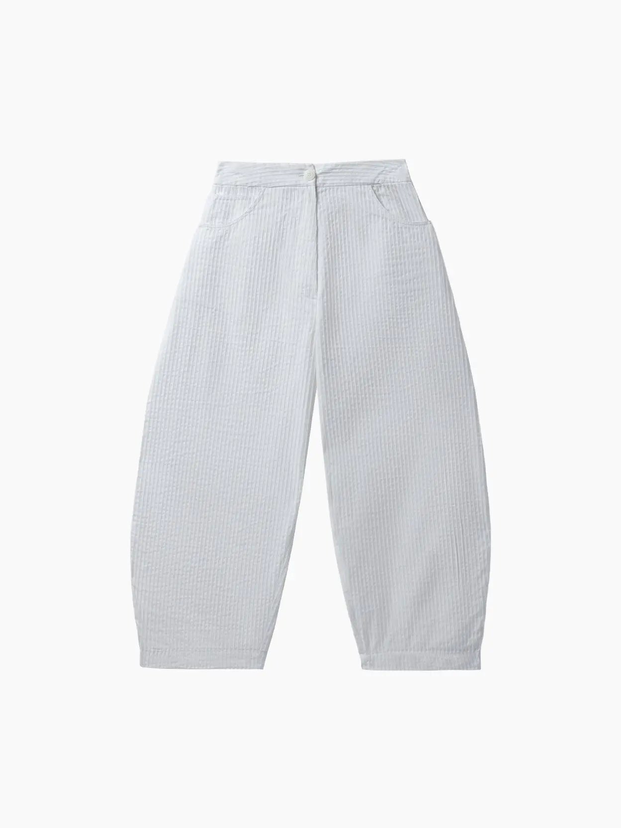 A pair of Tubular Curved Pants White from Cordera. The pants feature a high waist with a button and zipper closure, along with two front pockets. The fabric appears soft and slightly textured. Available at Bassalstore in Barcelona.