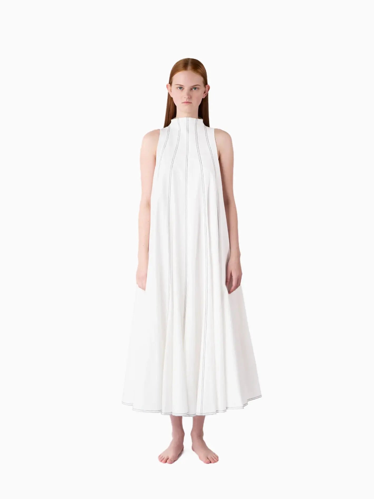 A Sunnei Tulipano Dress: a sleeveless white dress with a high neckline and a full, flowing skirt. The dress features vertical stitching details that run from the neckline down the bodice and along the skirt, creating a structured look. Available at BassalStore in Barcelona. The background is plain white.