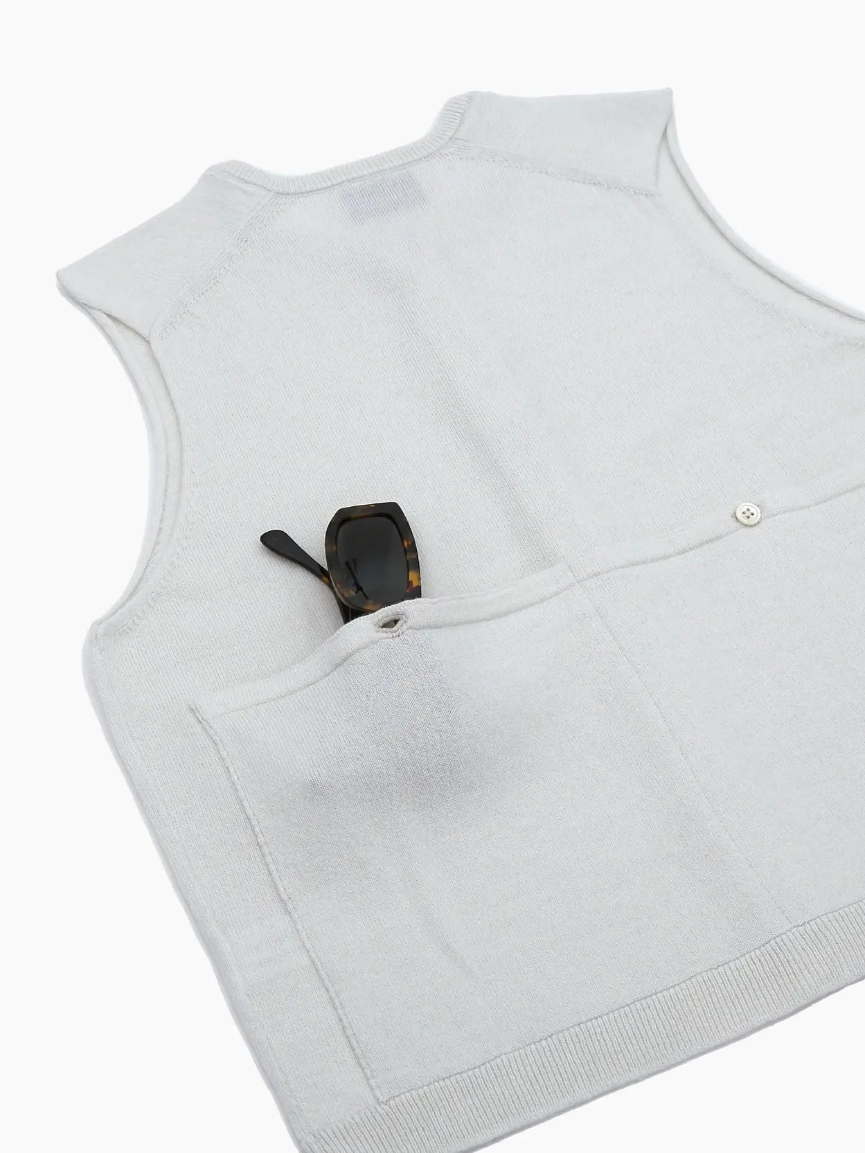 A light gray, sleeveless, button-up knit vest is shown against a white background. The vest has a round neckline and features a series of buttons down the front. The label inside the collar reads "Bielo," exclusively available at Bassalstore in Barcelona.