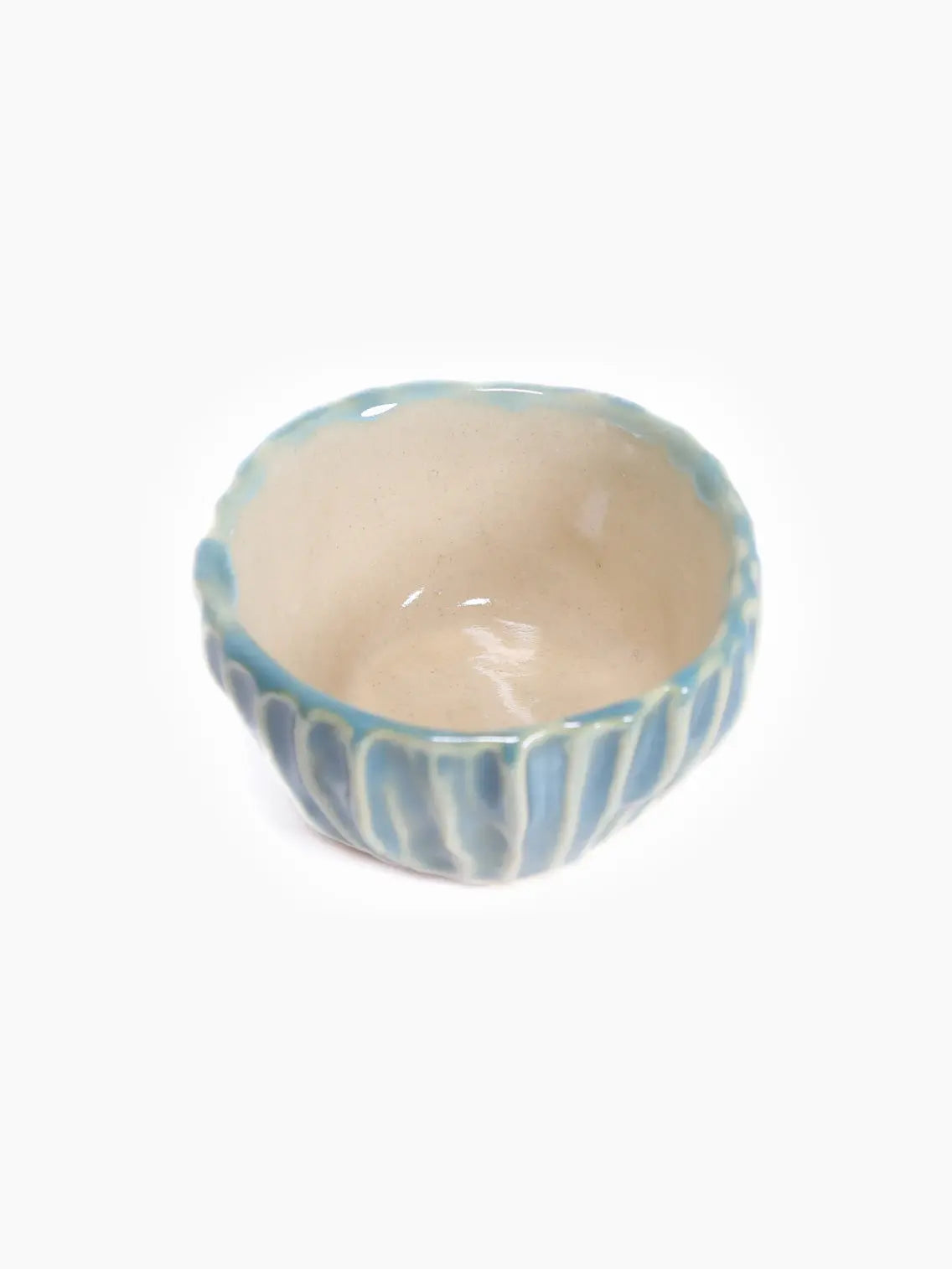 A small, handmade Bol Petit D from ipunto Ceramics is displayed on a white background. The bowl features a textured surface with vertical blue and white striped pattern, giving it a rustic and artisanal appearance reminiscent of Barcelona's charm. The rim of the bowl has a slightly irregular, wavy form.