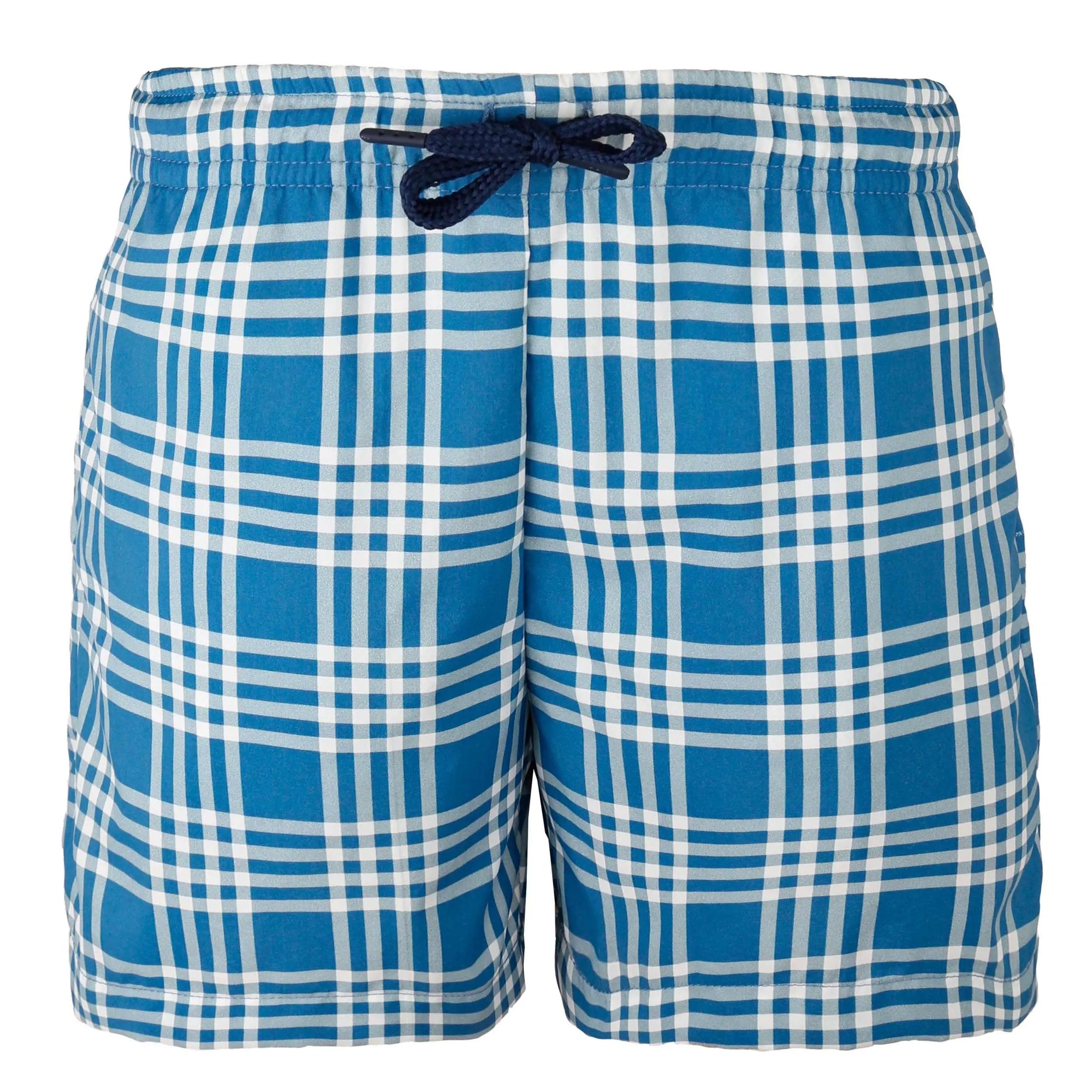 A neatly folded pair of blue and white plaid Cuatro Kids Swimwear with a navy blue drawstring is displayed inside an orange-bordered gift box. The box lid, featuring the brand name "Bassal." from the popular Bassalstore in Barcelona, is partially visible on the side. A tag with "Bassal. kids" is attached to the swimwear.