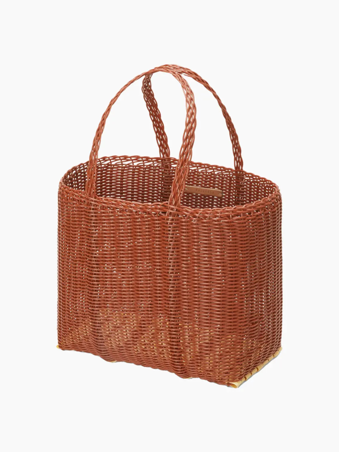 A rectangular, brown wicker handbag with sturdy double handles. The woven texture and earthy tone give it a rustic, natural appearance. Perfect for a day out in Barcelona, the Flat Small Clay Bag by Palorosa has a spacious interior, stylishly designed for practicality and fashion. Available now at Bassalstore.