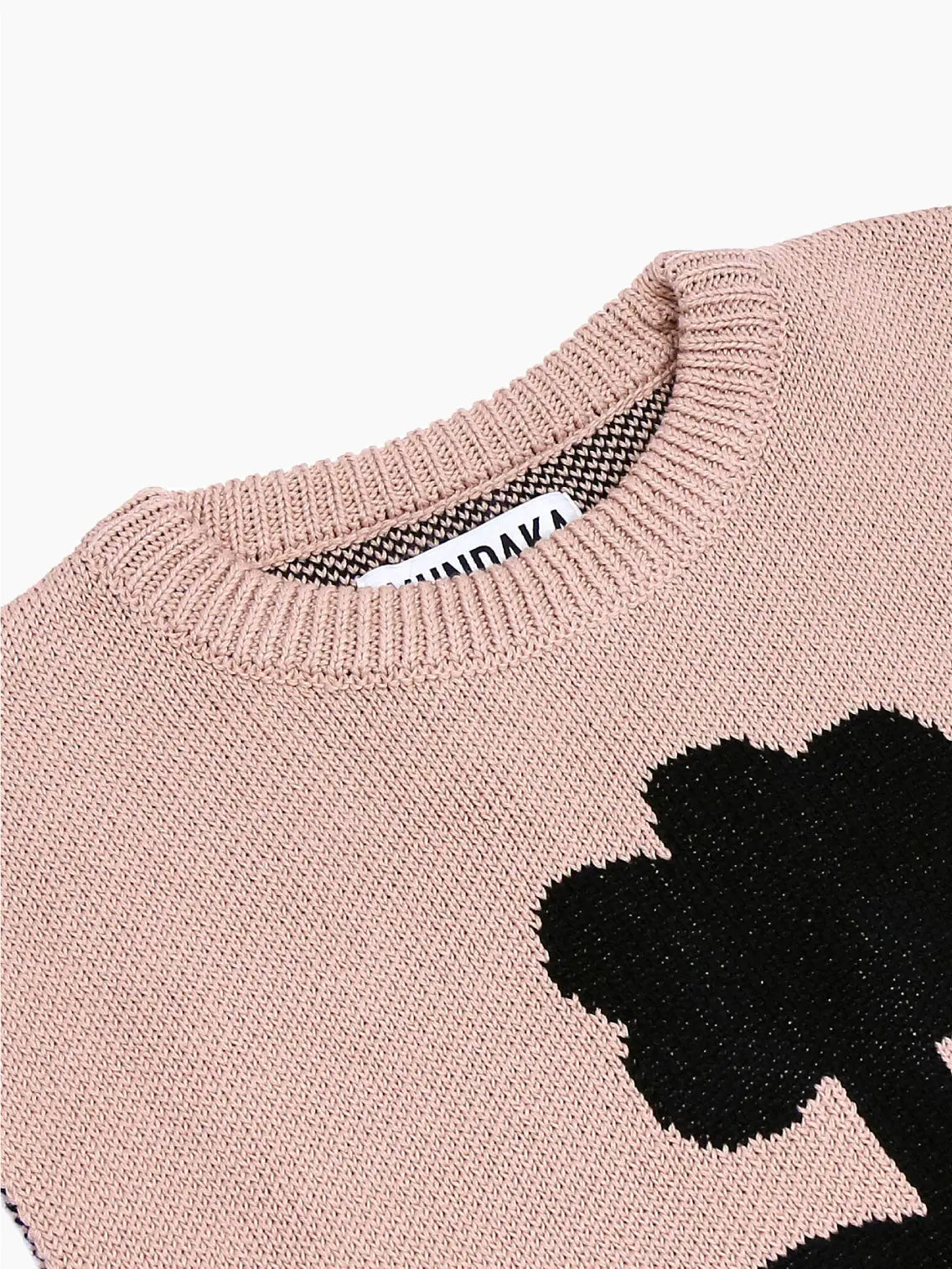 A sleeveless, light pink knit sweater with a black, minimalist flower design in the center. The sweater features a crew neck and a visible brand tag at the neckline. Photographed against a plain white background, this exquisite Flower Vest Beige from Mundaka captures the essence of Barcelona fashion effortlessly.