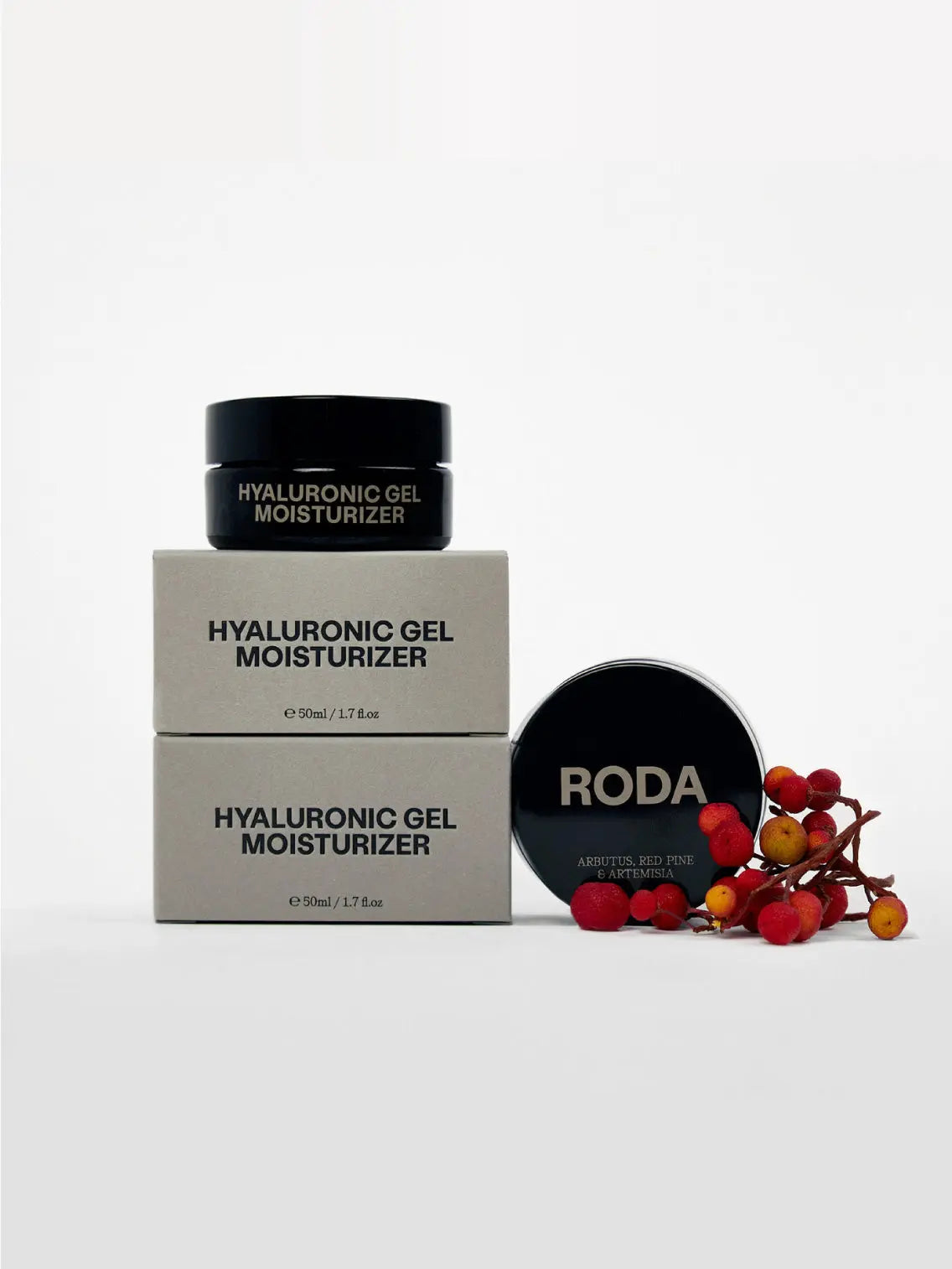 A beige box labeled "Roda Hyaluronic Gel Moisturizer," featuring "Arbutus, Red Pine & Artemisia" in smaller text, sits beside an open round black container with the same label. A small bunch of red berries lies to the right of the container, a signature offering at Bassal Store in Barcelona.