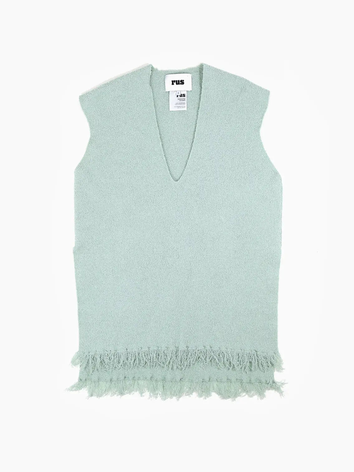 A Katsura Top Green with a deep V-neck and a fringe trim at the hem. The label inside the collar area reads "Rus," and additional garment care and size tags are visible underneath. This chic piece, available at BassalStore in Barcelona, is laid flat against a plain white background.