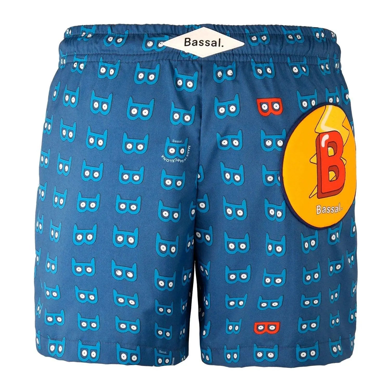 A pair of blue Mask Kids Swimwear with a cute owl pattern, neatly folded in an orange-bordered white box. A tag with the brand name "Bassal" and a plastic zipper bag are visible. The brand's name "Bassalstore" is printed on the box, showcasing its Barcelona roots.