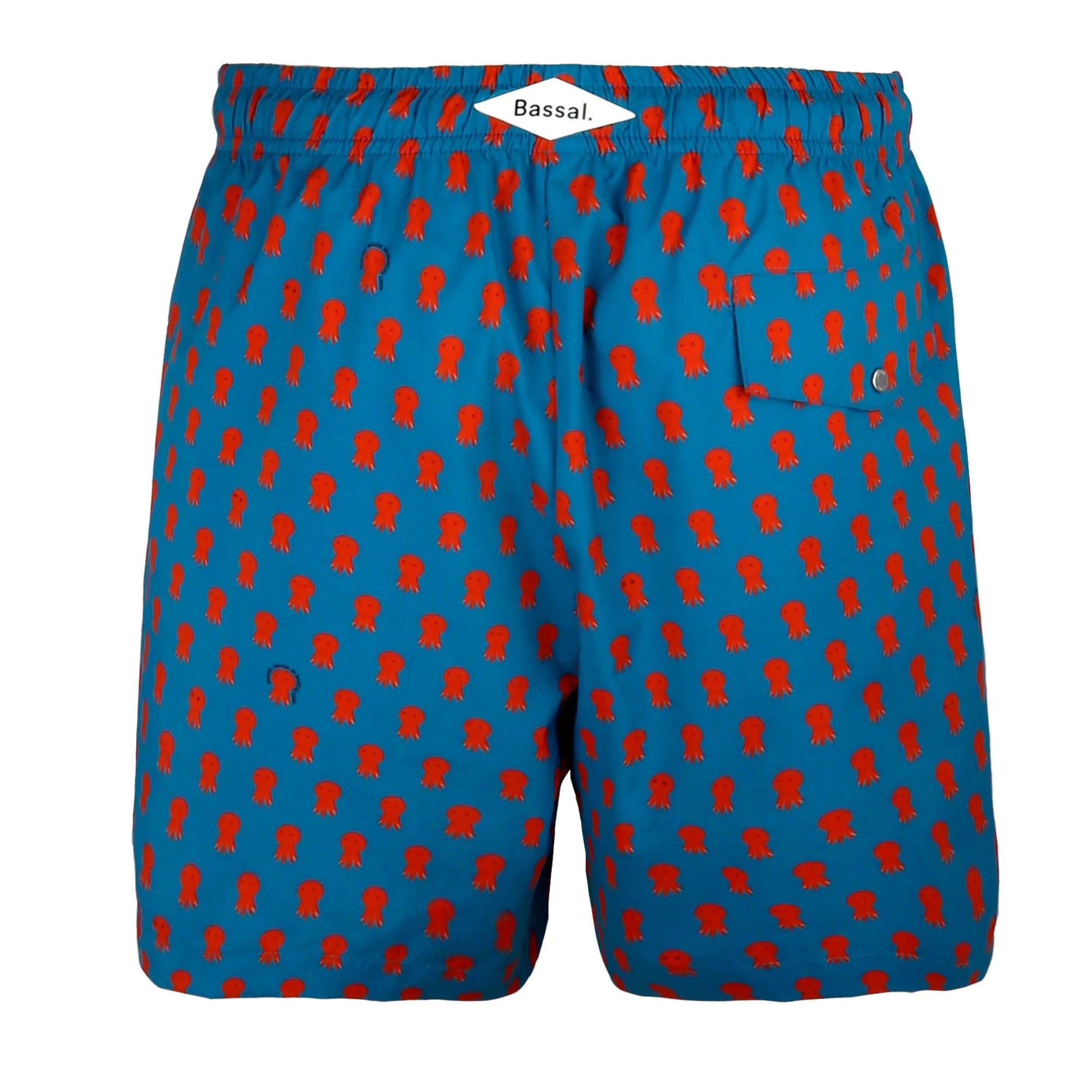 A neatly packed pair of Octo Swimwear with an orange octopus pattern is displayed in an open white box. The waistband is elastic with a blue drawstring. A tag labeled "Bassal" is attached to the swimwear, which are folded and arranged tidily inside the box.
