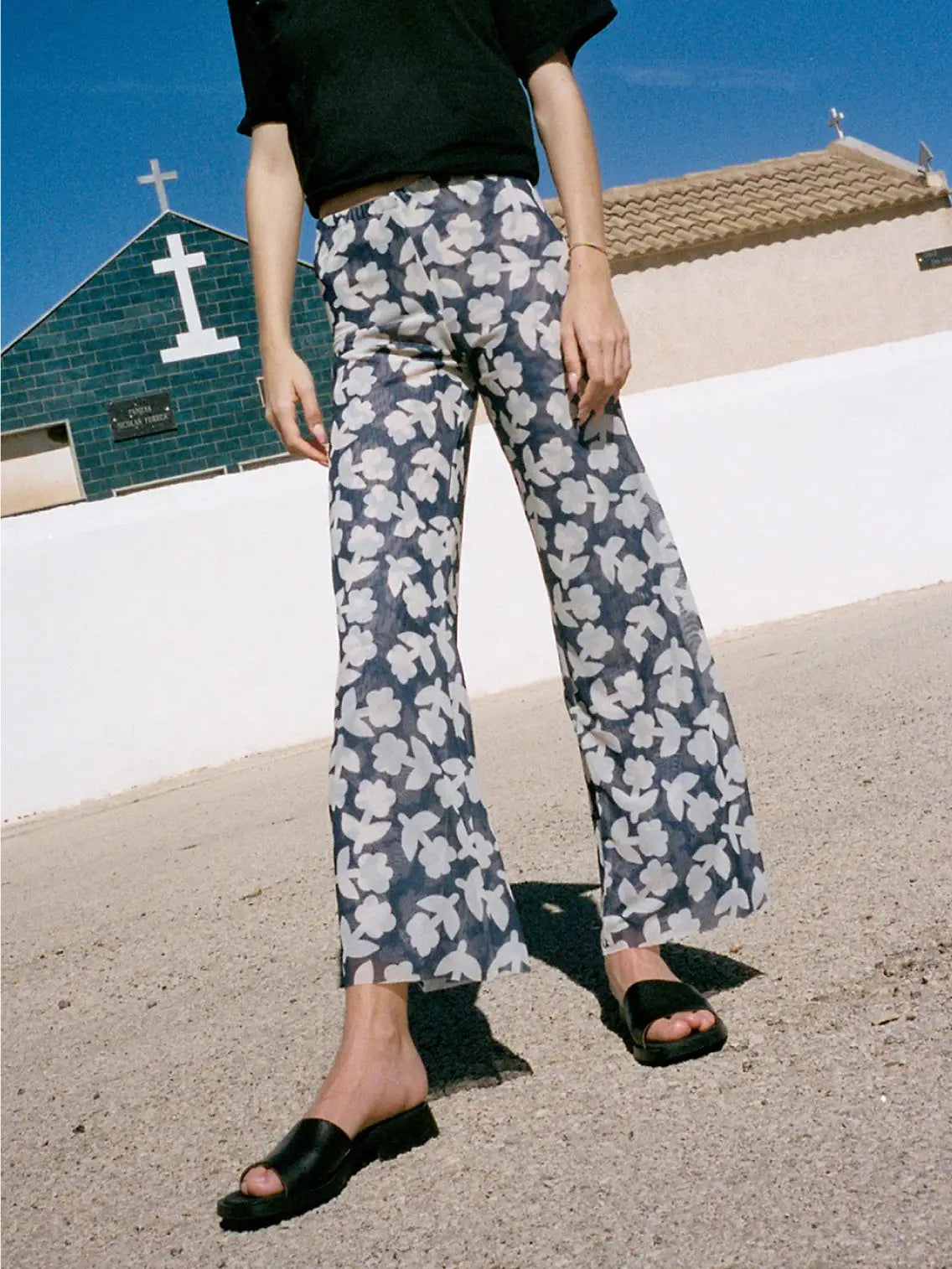 A pair of Recycled Tulle Pants Blue by Mundaka with a dark blue background and a white floral pattern spread evenly across the fabric, available at Bassalstore in Barcelona. The pants feature an elastic waistband at the top.