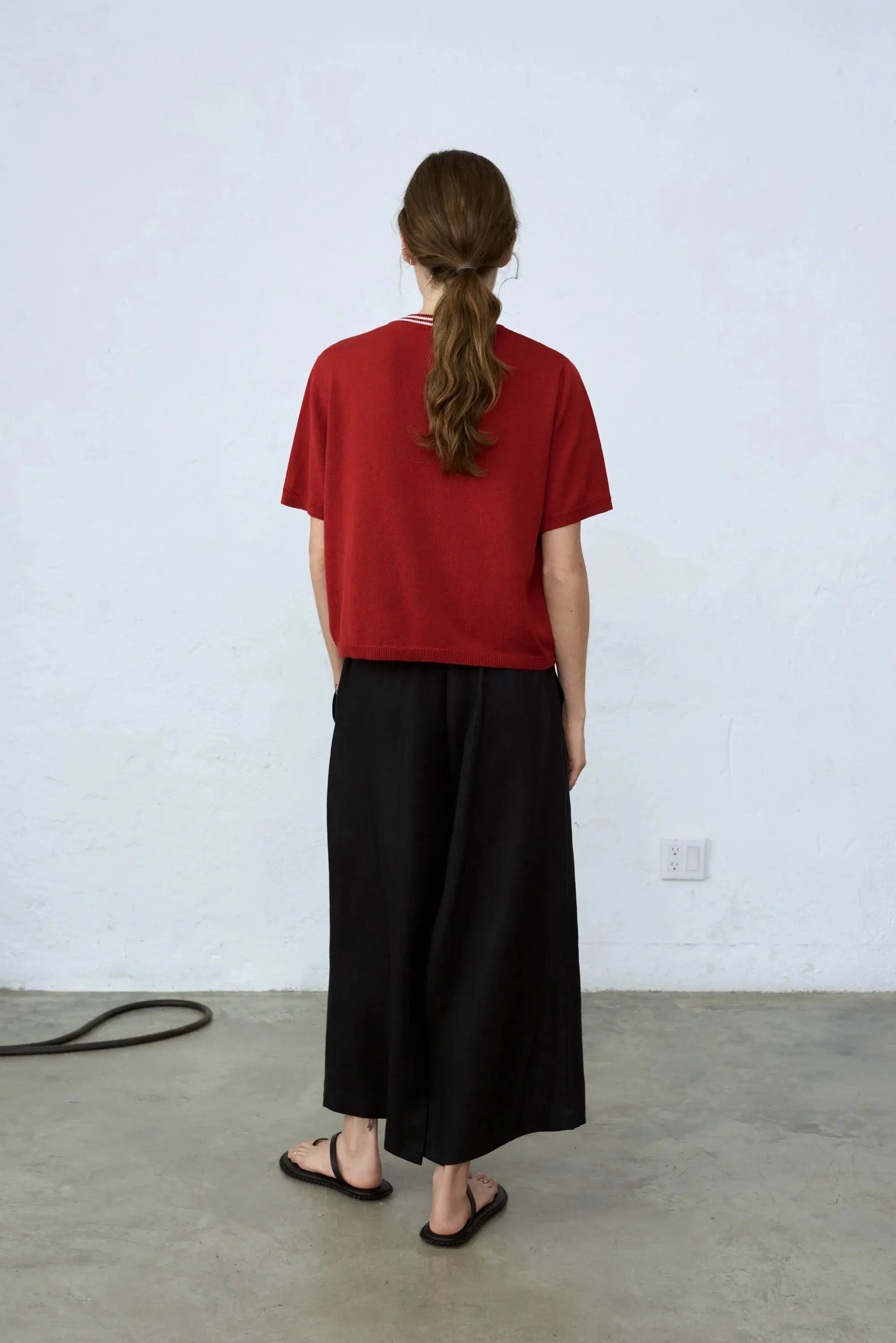 A red Silk Logo Top Red with a ribbed neckline, featuring a small white text logo on the left chest. The neckline has white striped detailing, and there are additional small stitched details near the shoulders. Available exclusively on BassalStore from Cordera, it's perfect for your next trip to Barcelona.
