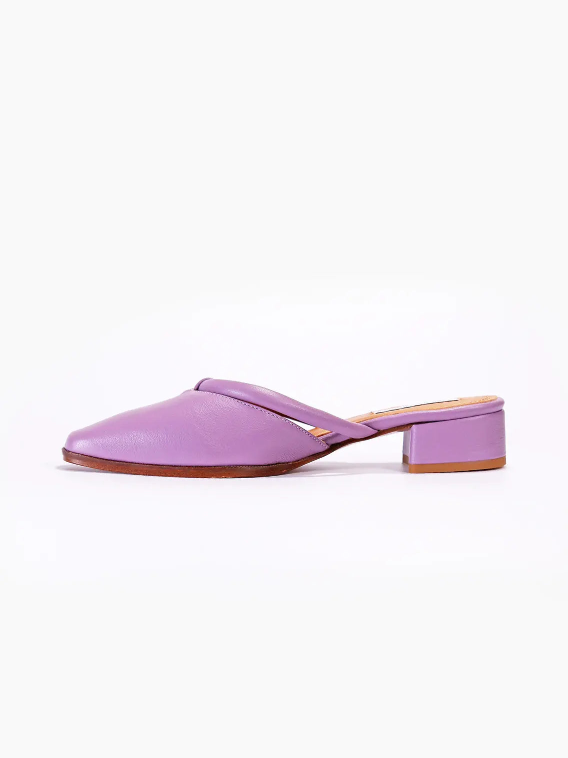 A fashionable lilac open-back mule shoe from Bassalstore features a sleek design with a low block heel and pointed toe. The Simone Floresta Sandals from About Arianne are made of smooth material with a subtle sheen, enhancing their elegant appearance. The inner sole appears cushioned for comfort, perfect for strolling through Barcelona.