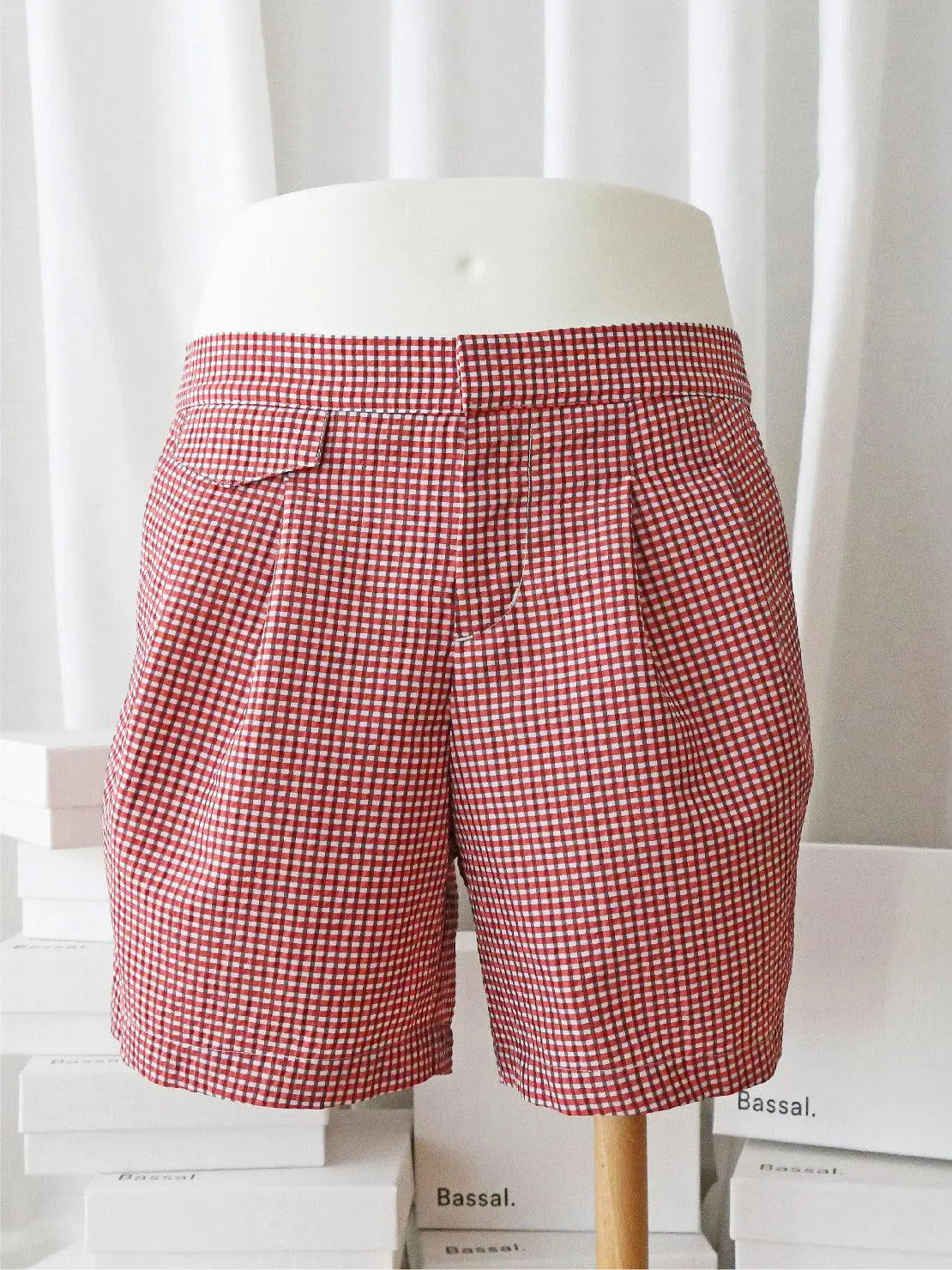 A pair of red and white gingham checkered Taia Red Swimwear with a high waist and pleats at the front, available exclusively at Bassalstore in Barcelona. These lightweight swimwear pieces feature two side pockets, making them ideal for casual summer wear.