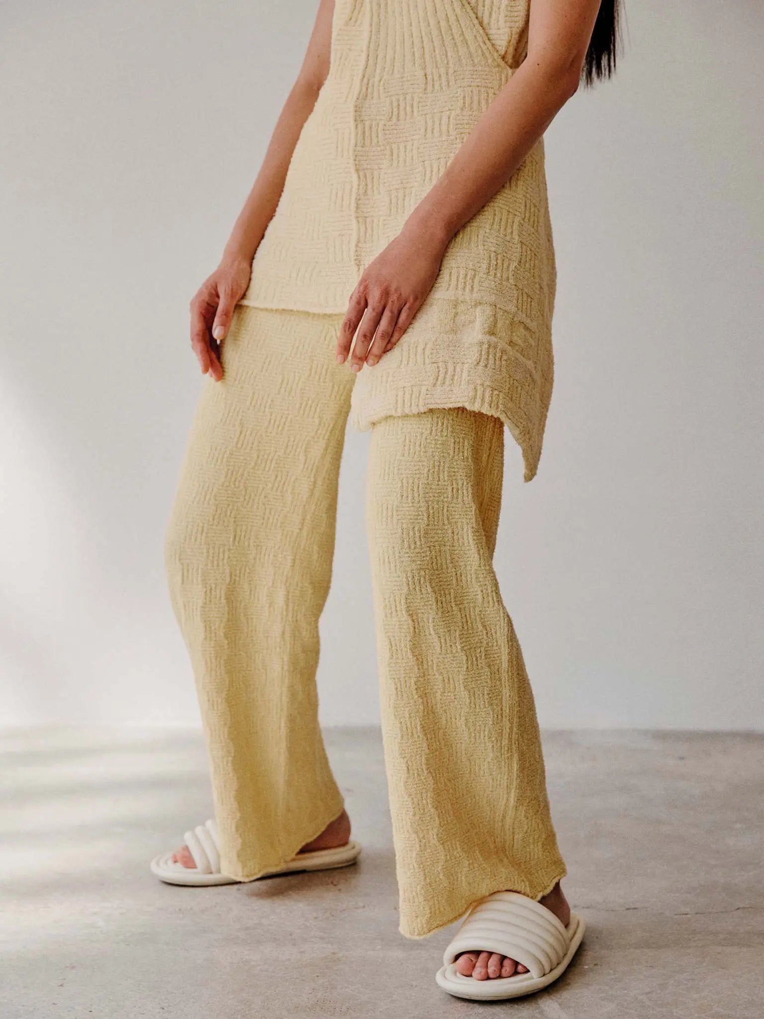A pair of Tofu Pants Yellow from Rus with a flared leg from BassalStore. The waistband is ribbed, and the pants feature a subtle wavy pattern throughout. The fabric appears soft and cozy, suitable for casual or lounge wear.