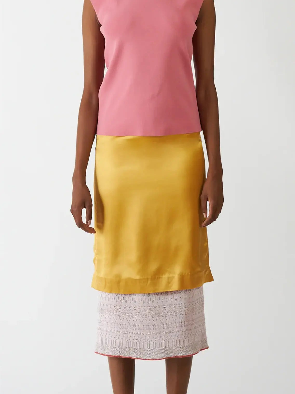 A person is wearing a sleeveless pink top paired with the Bielo Vivi Skirt Dore, which features a white crocheted lace trim at the hem. The outfit, showcasing vibrant colors, is displayed in front of a plain white background. This chic ensemble can be found at Bassalstore in Barcelona.